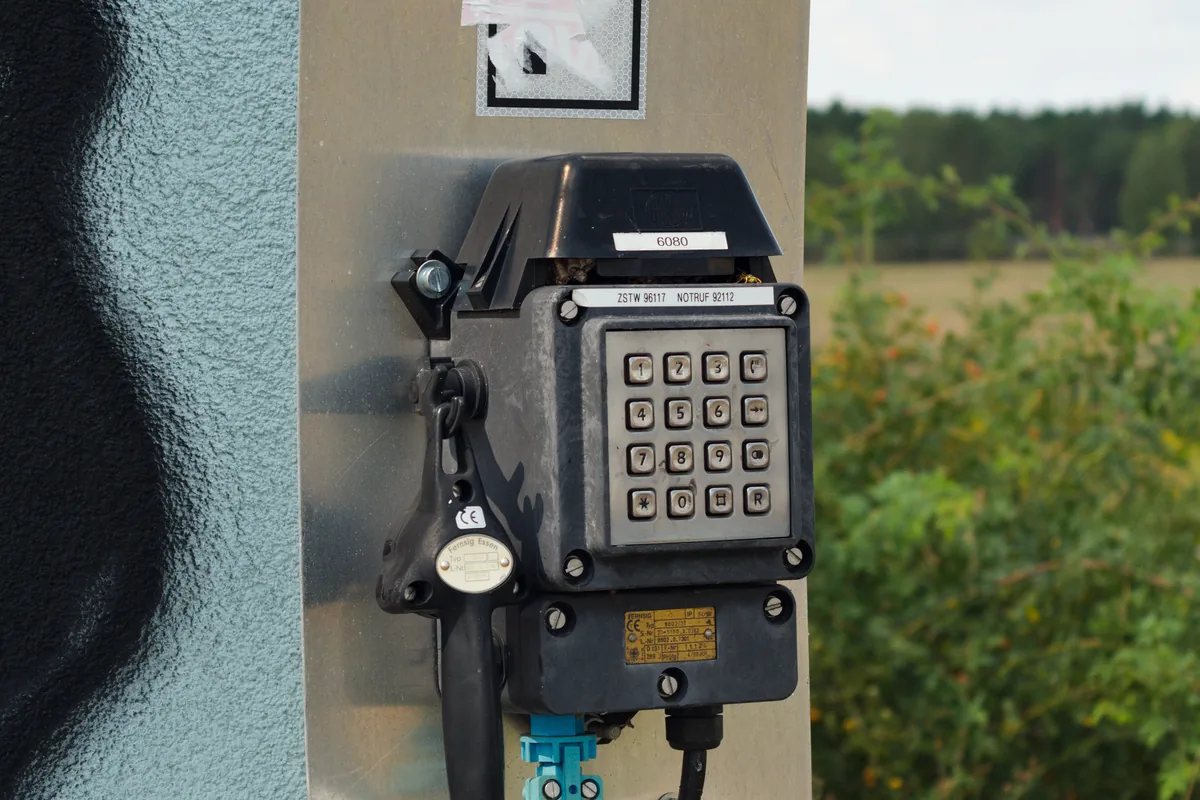 Weatherproof track-side telephone on a post beside the coal railway of an open-pit lignite mine, the kind of fixed mine telephone point an MGM 110 armoured telephone cable connects