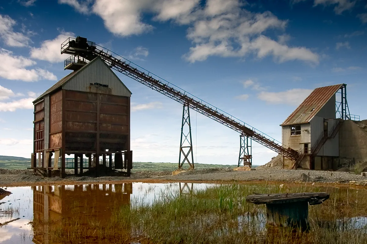 Mine rock crusher house with an inclined conveyor gantry, a surface crushing plant of the type fed by MGM 112 Type E4 armoured power cable