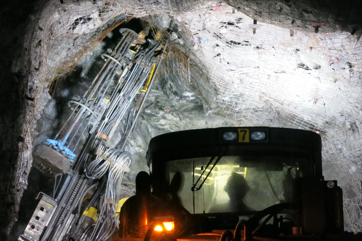 Drill rig working at the face of a mesh-supported underground mine drift, the kind of drilling duty an MGM 115 Type 14 trailing cable supplies