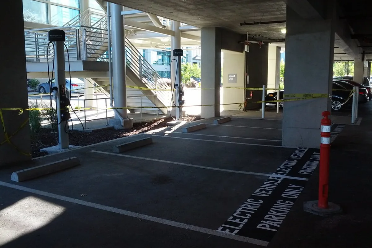 Covered workplace car park with EV charging posts beside marked electric vehicle bays, an internal route for a combined power and CAT5e data cable