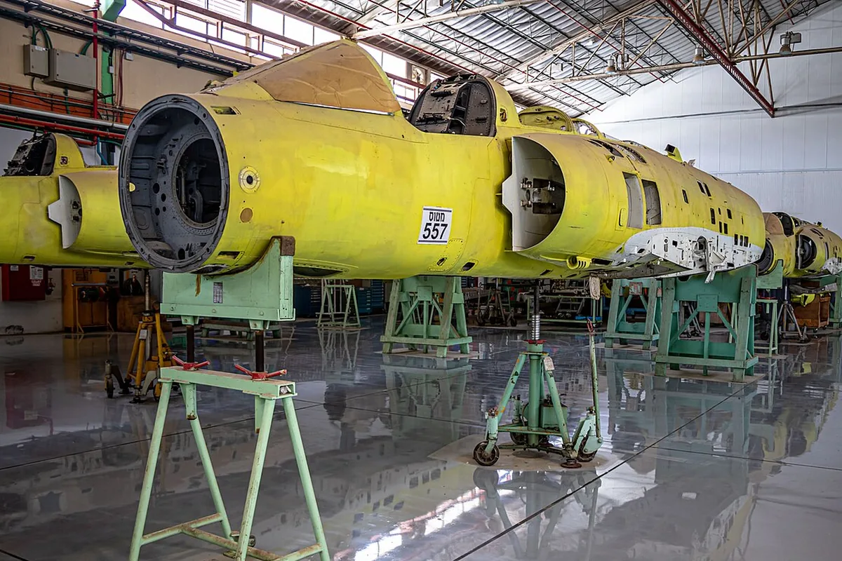 Aircraft fuselage sections held on support stands and jacks in an assembly hall, where mobile support robots trail a hybrid power, control and data cable