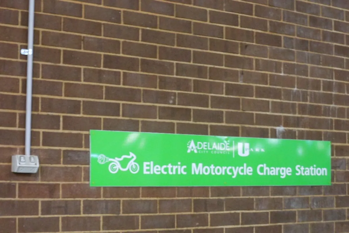 Wall-mounted socket-outlet beside an electric motorcycle charge station sign, the kind of supply point a mode 1 H05BZ5-F charging lead plugs into