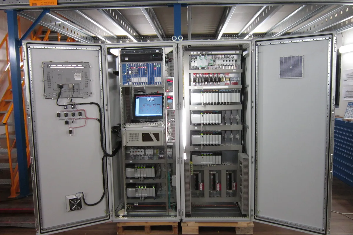 Open PLC control cabinet with controller modules, terminal rows and an operator screen, the kind of panel where LiYY multicore cable carries low-voltage signals