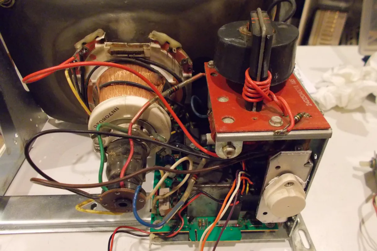 Inside a CRT computer monitor, coloured lead wires run from the circuit board to the deflection yoke and the high-voltage transformer, the kind of appliance wiring that uses 150 °C UL 1164 PTFE wire