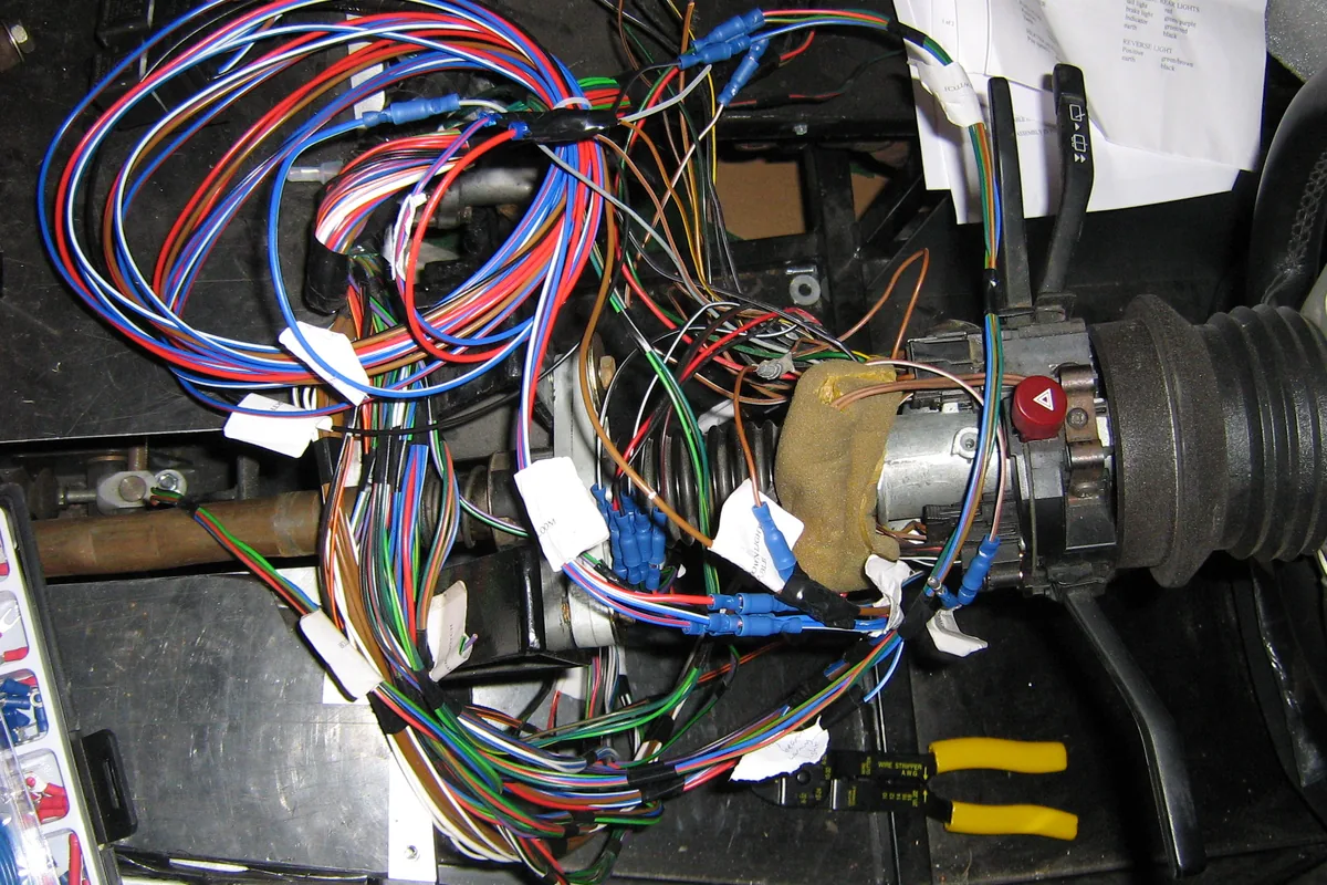 Loom of thin coloured hook-up wires being connected to a vehicle steering column and lighting relays, the kind of compact wiring where 300 V, 125 °C UL 3266 XLPE wire is used